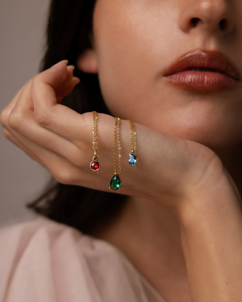 Hand holding colorful pendant necklaces