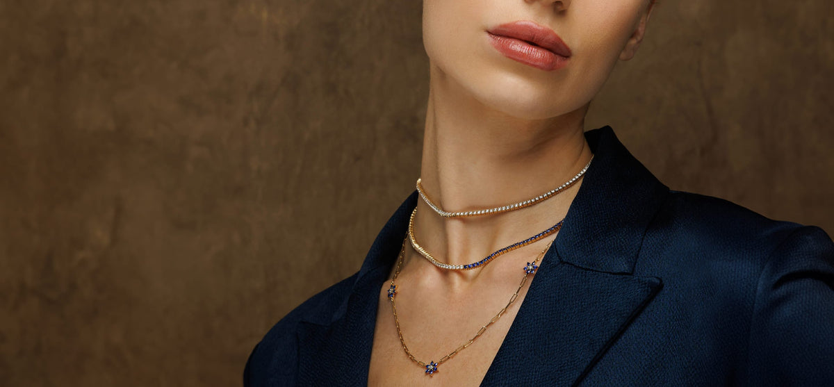 Model in a navy blazer wearing layered gold necklaces